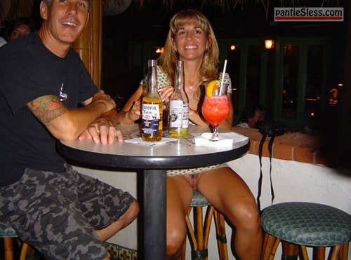 bottomless  Pretty girl smilingly flashing her pussy in a bar. The guy is...